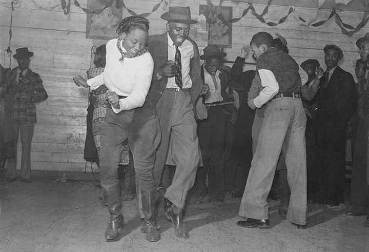 African American women and men dancing and smiling. 1930s juke joint. Rough floors. A party.