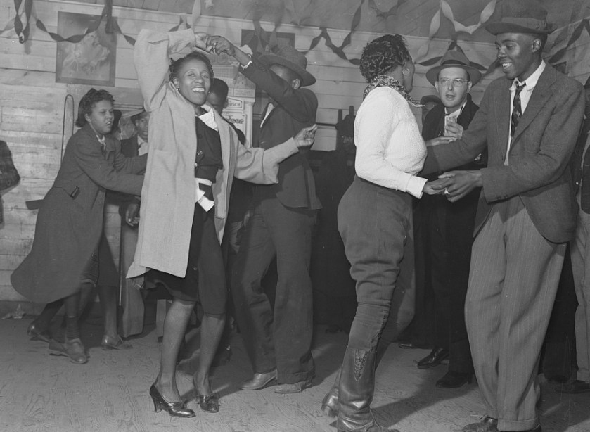 African American women and men dancing and smiling. 1930s juke joint. Rough floors. A party.